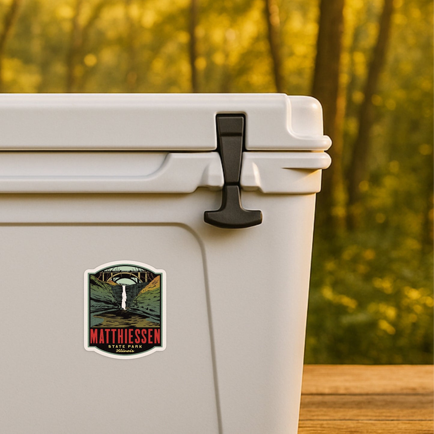 White cooler with a sticker on a wooden surface and blurred forest background