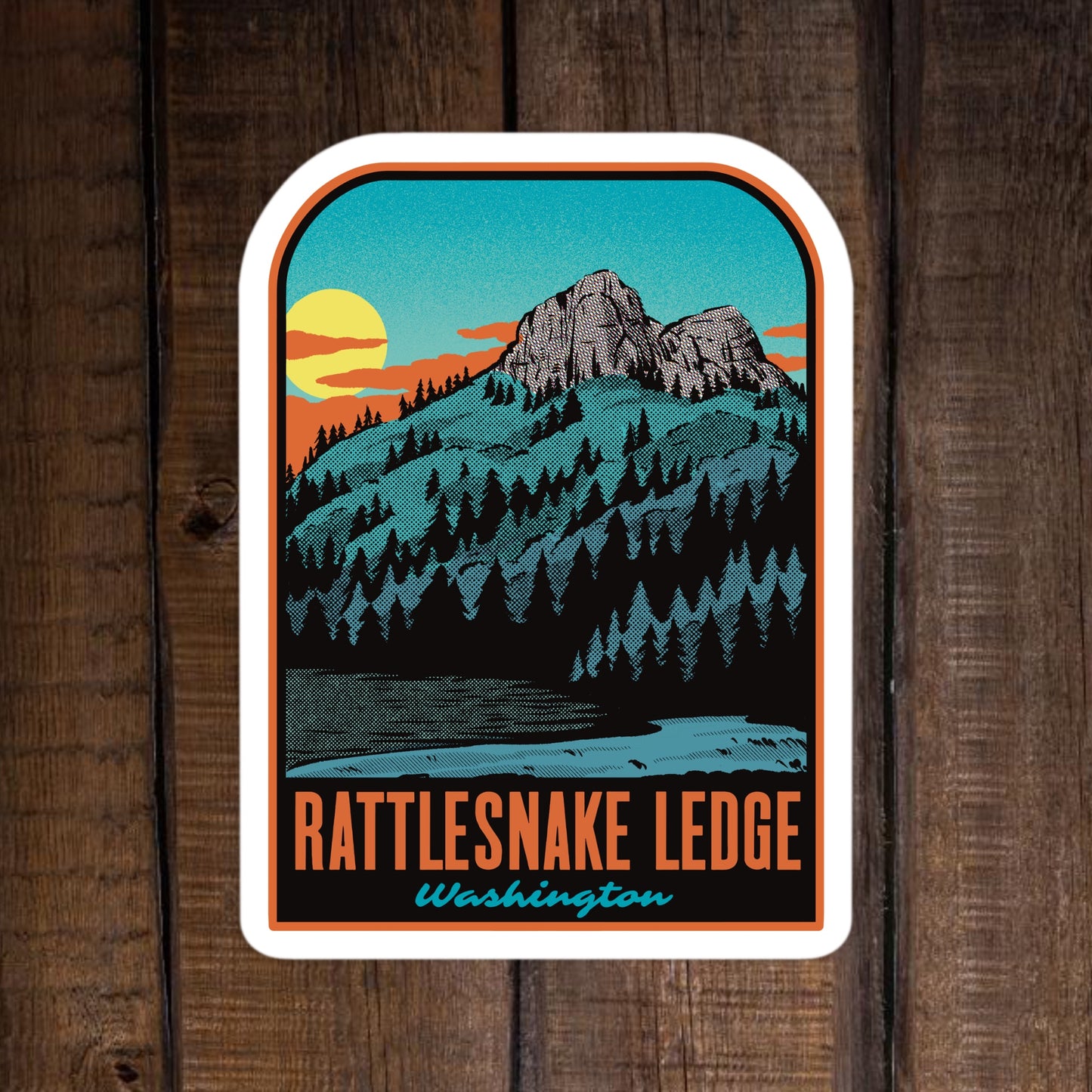Sticker with mountain landscape and 'Rattlesnake Ledge, Washington' text on a wooden background