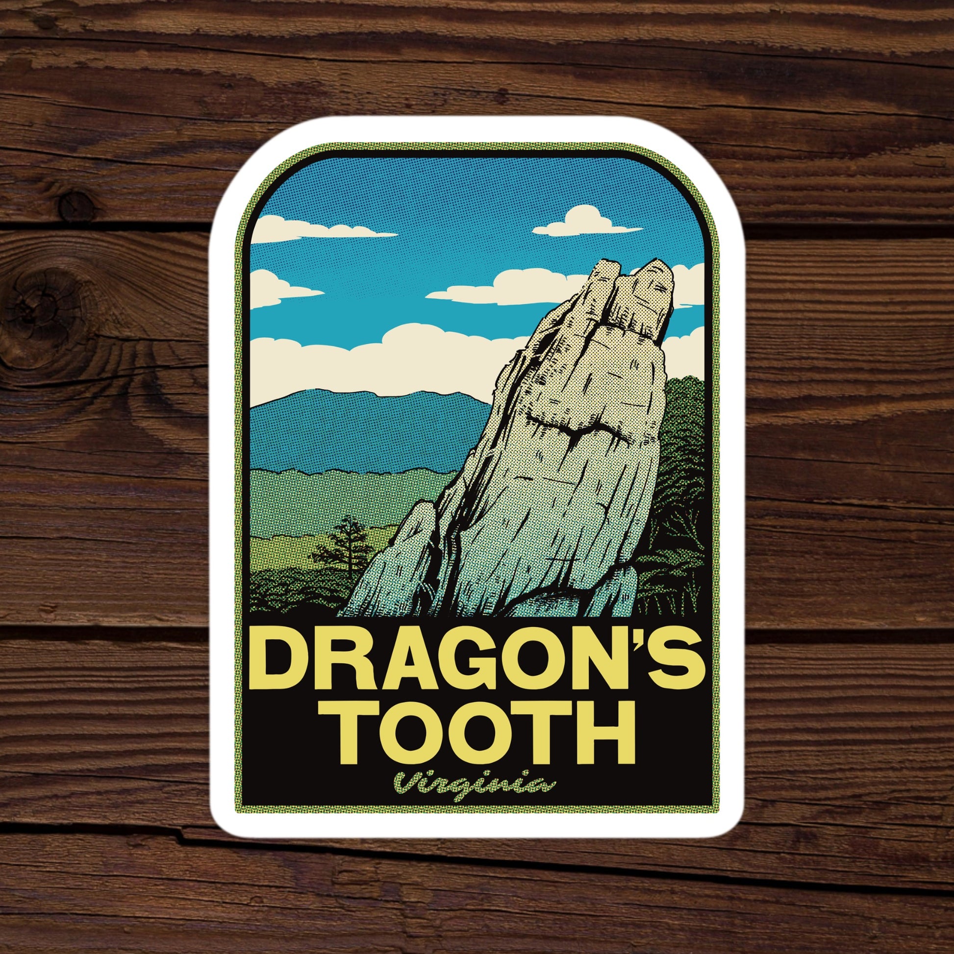 Sticker with a mountain design and 'Dragon's Tooth Virginia' text on a wooden background