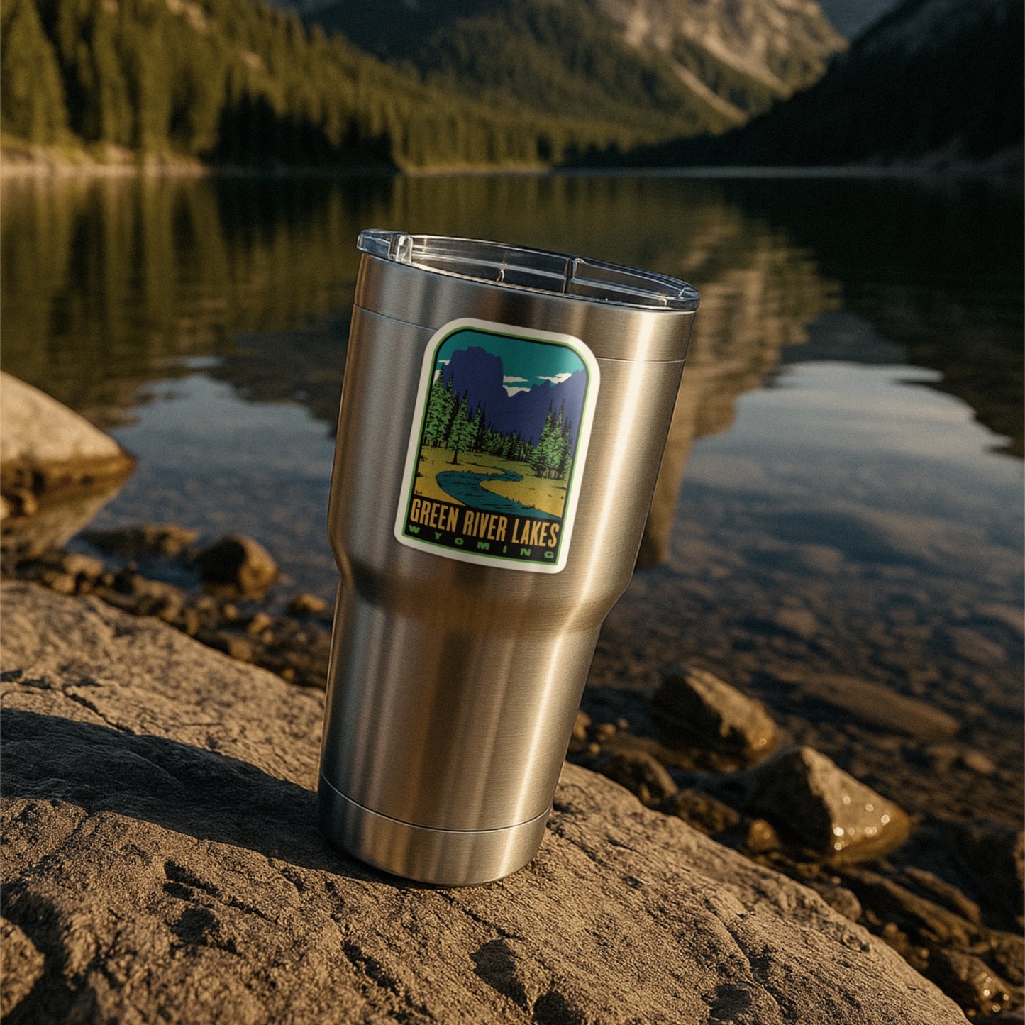 A sticker of Green River Lakes on a tumbler cup by a lake