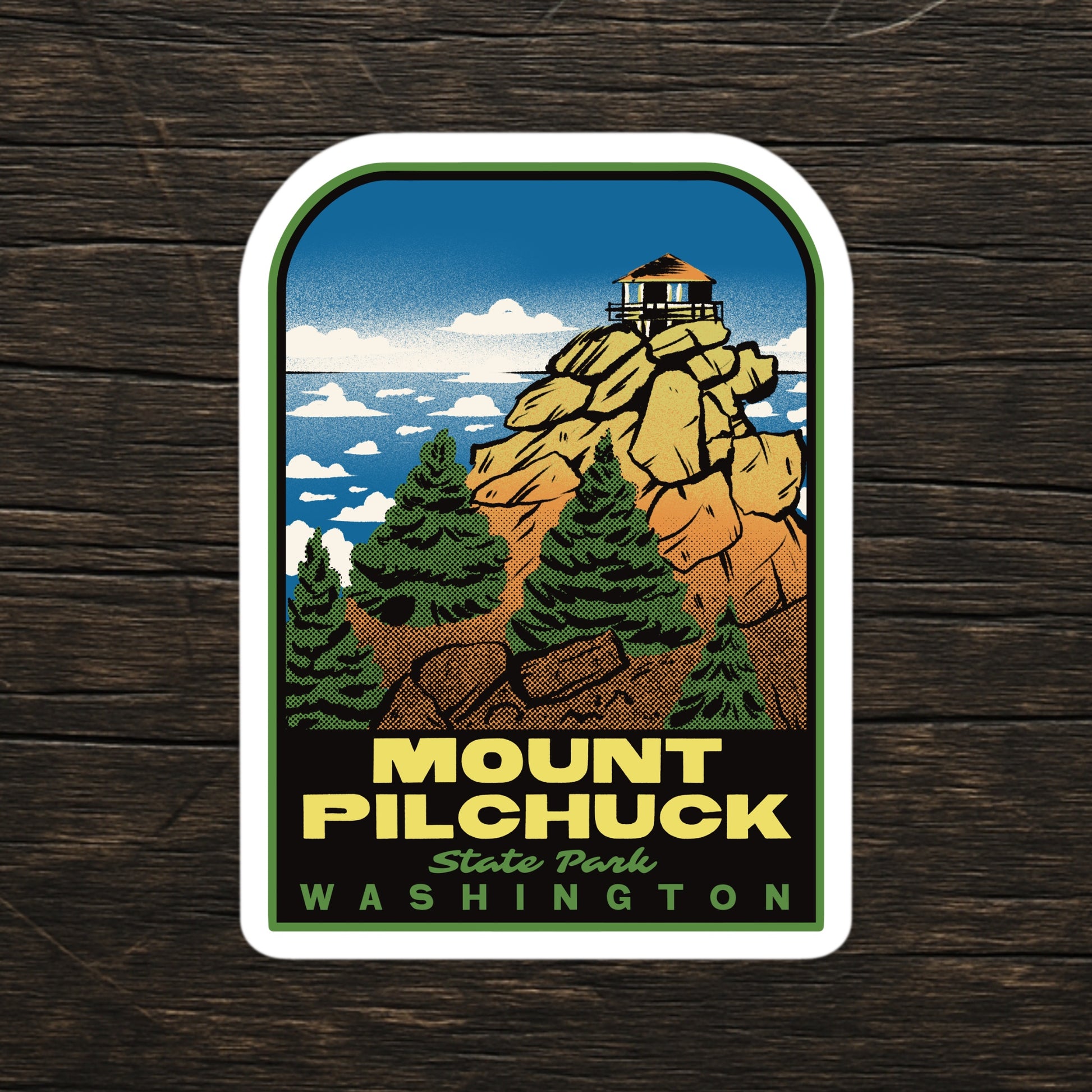 A sticker of Mount Pilchuck State Park Washington on a wood background