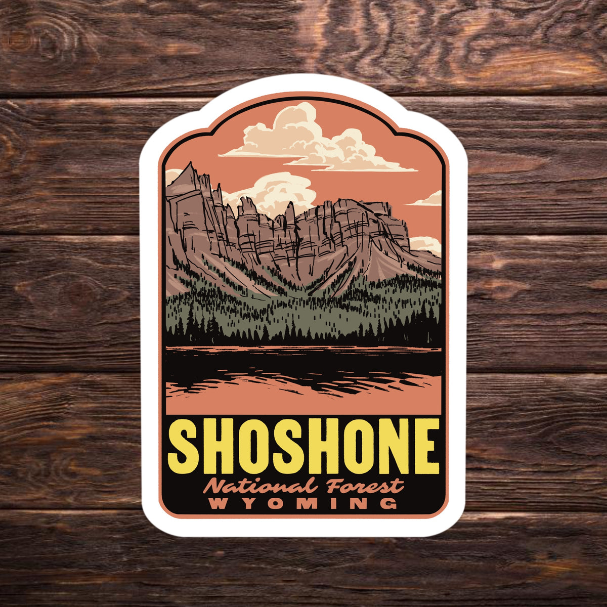 a sticker that reads "Shoshone National Forest Wyoming" on a wood surface
