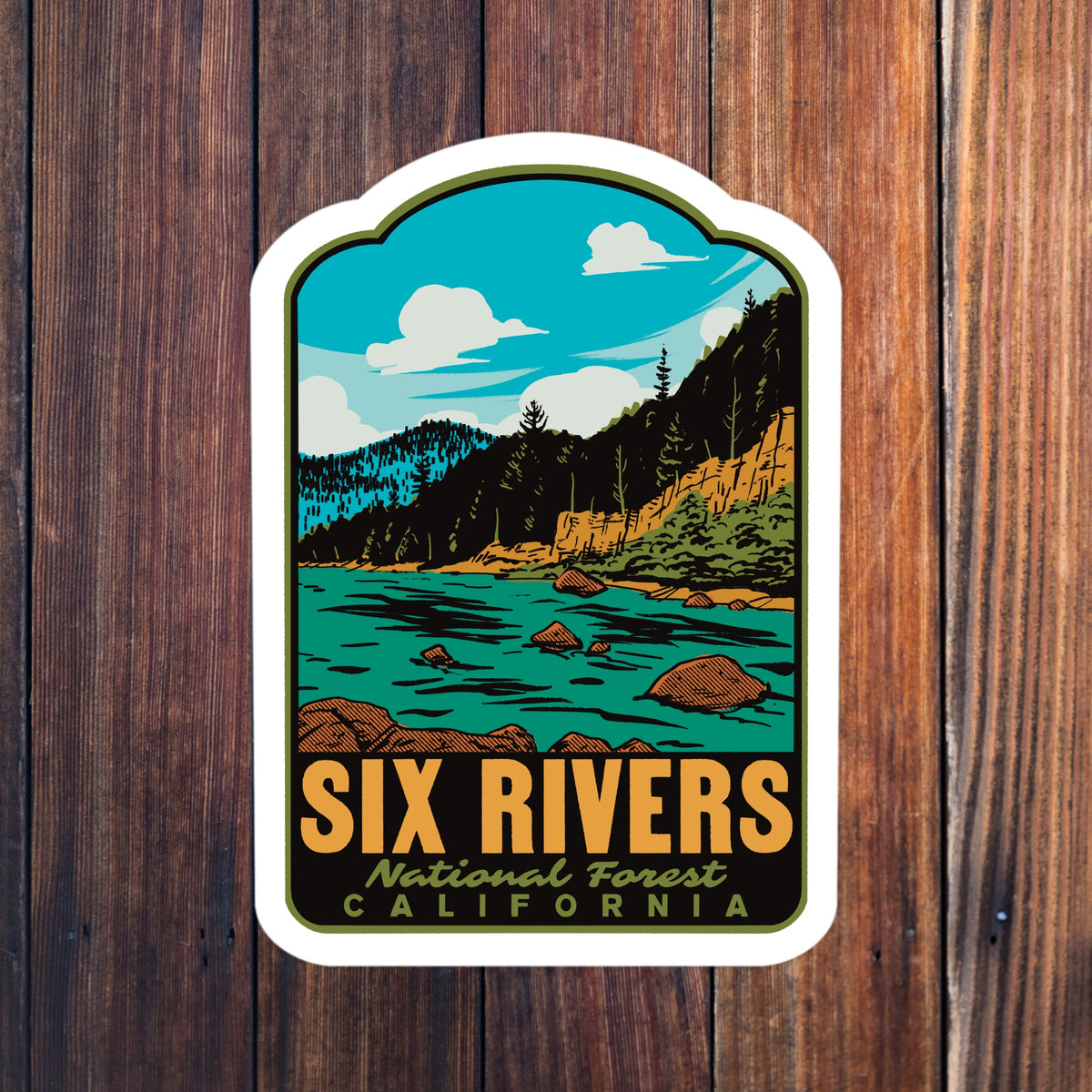 a sticker that reads "Six Rivers National Forest California" on a wood background
